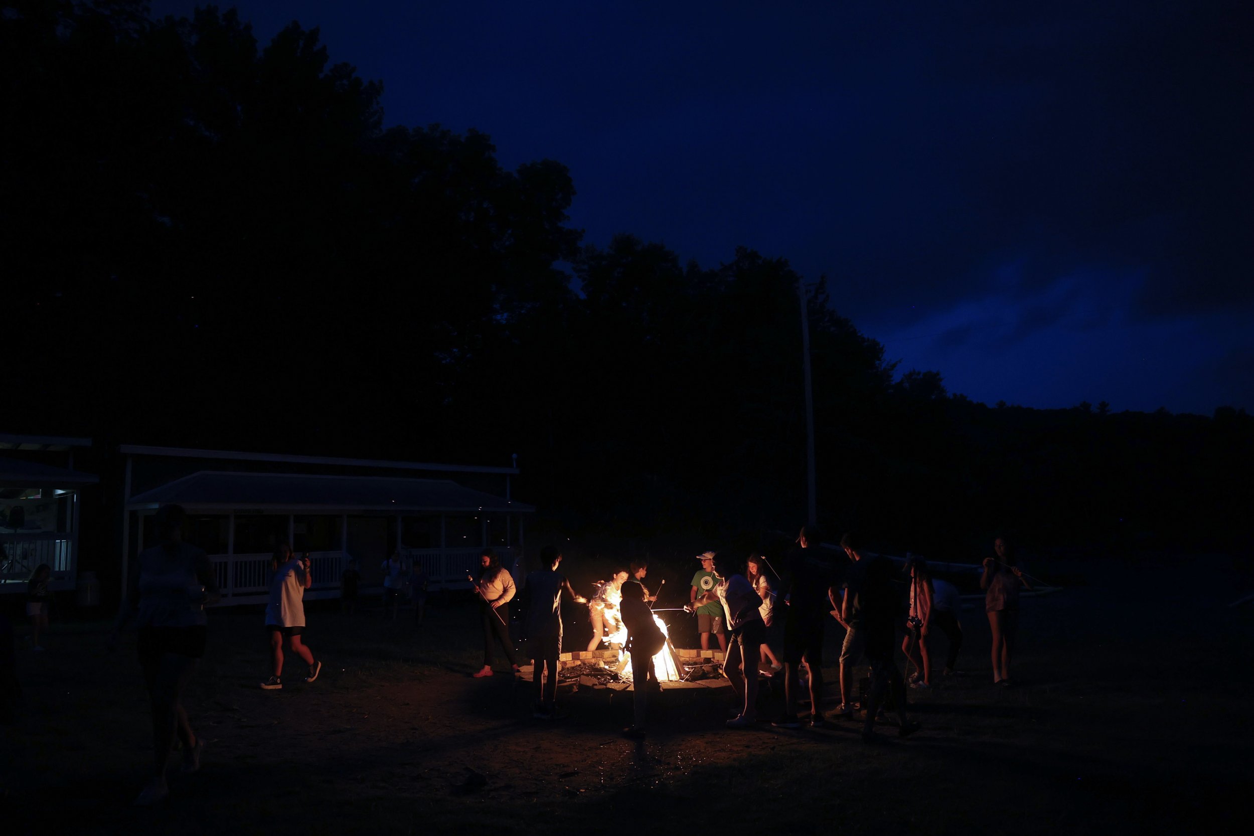  Campers roasts marshmallows at an evening bonfire by the lake on July 18, 2022.  