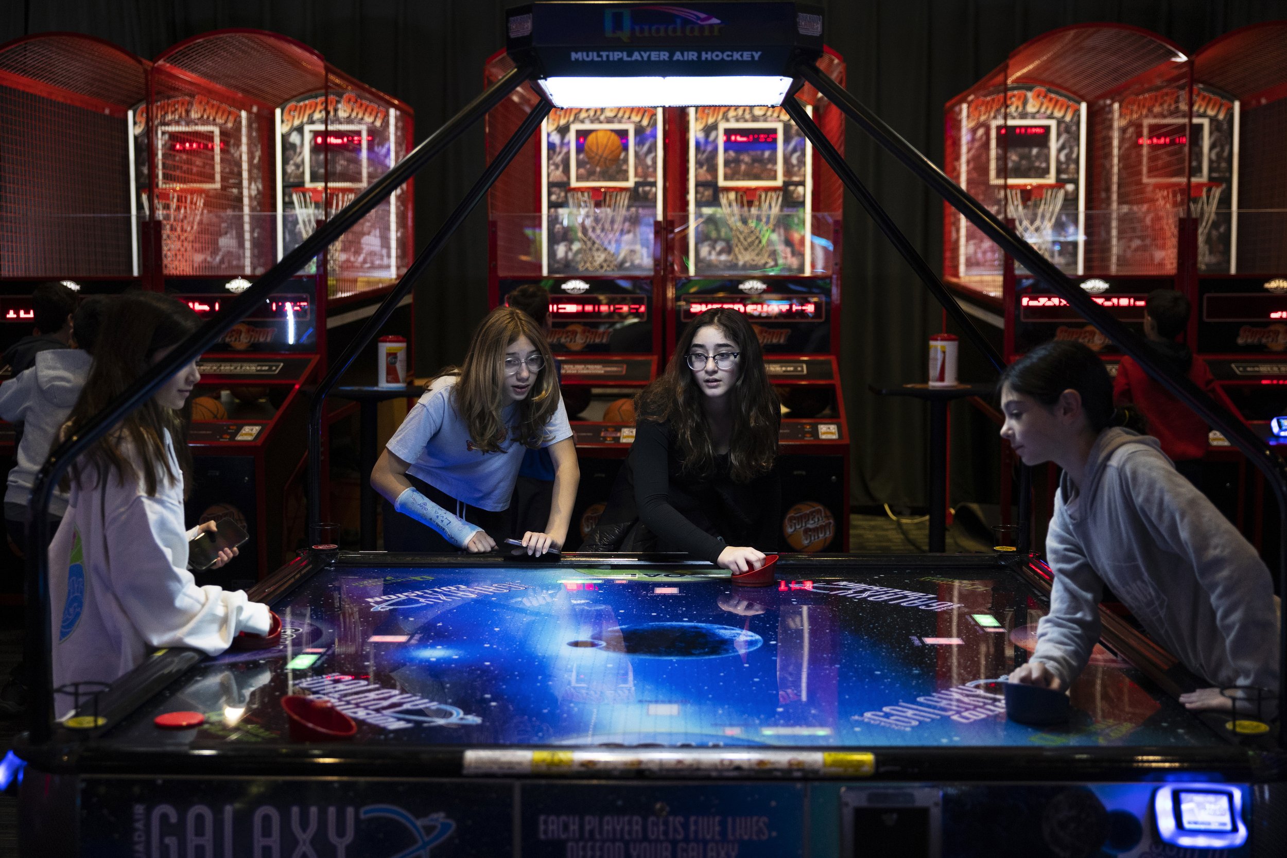  Carly Kreisler (second to left) and Daniella Goldberg (third to left) play air hockey with friends at the camp reunion at Dave and Busters in Palisades, New Jersey on November 27, 2022.  