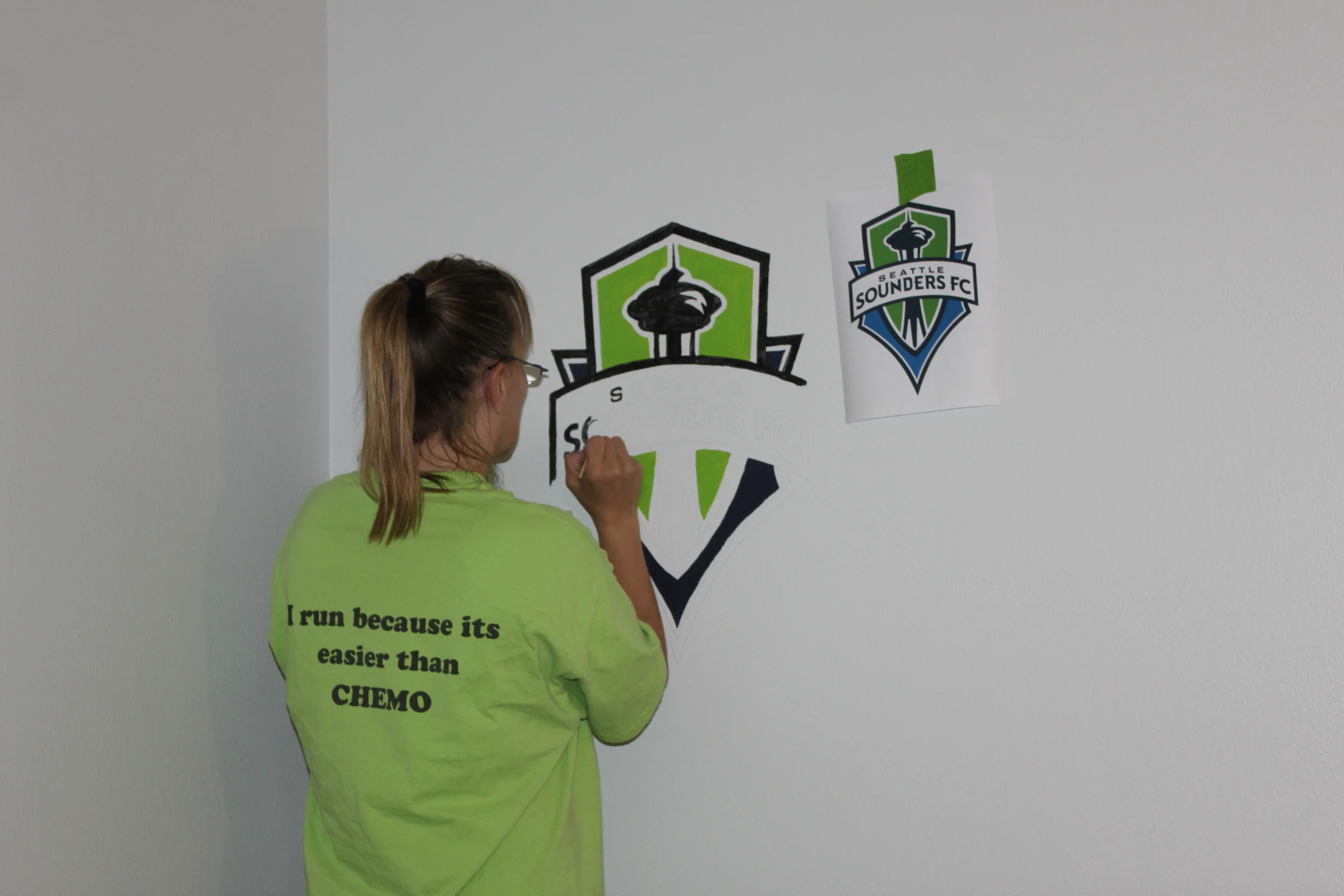 Doreen painting the Sounders logo on the wall. 
