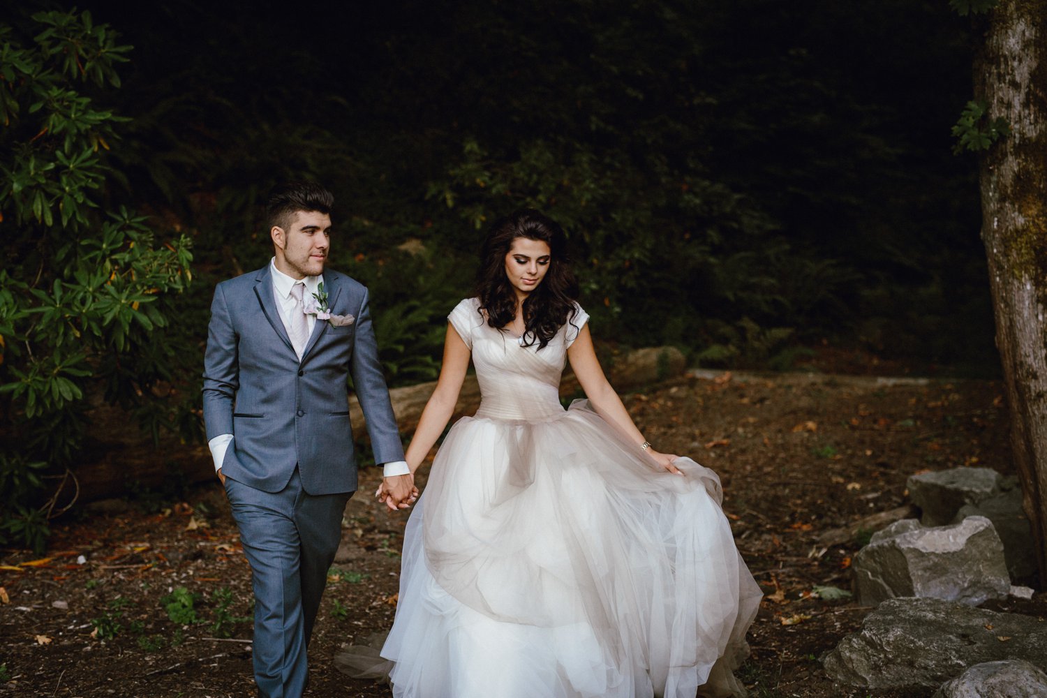 The bride and groom walk together in the Portland Rose Garden by photographer Catalina Jean