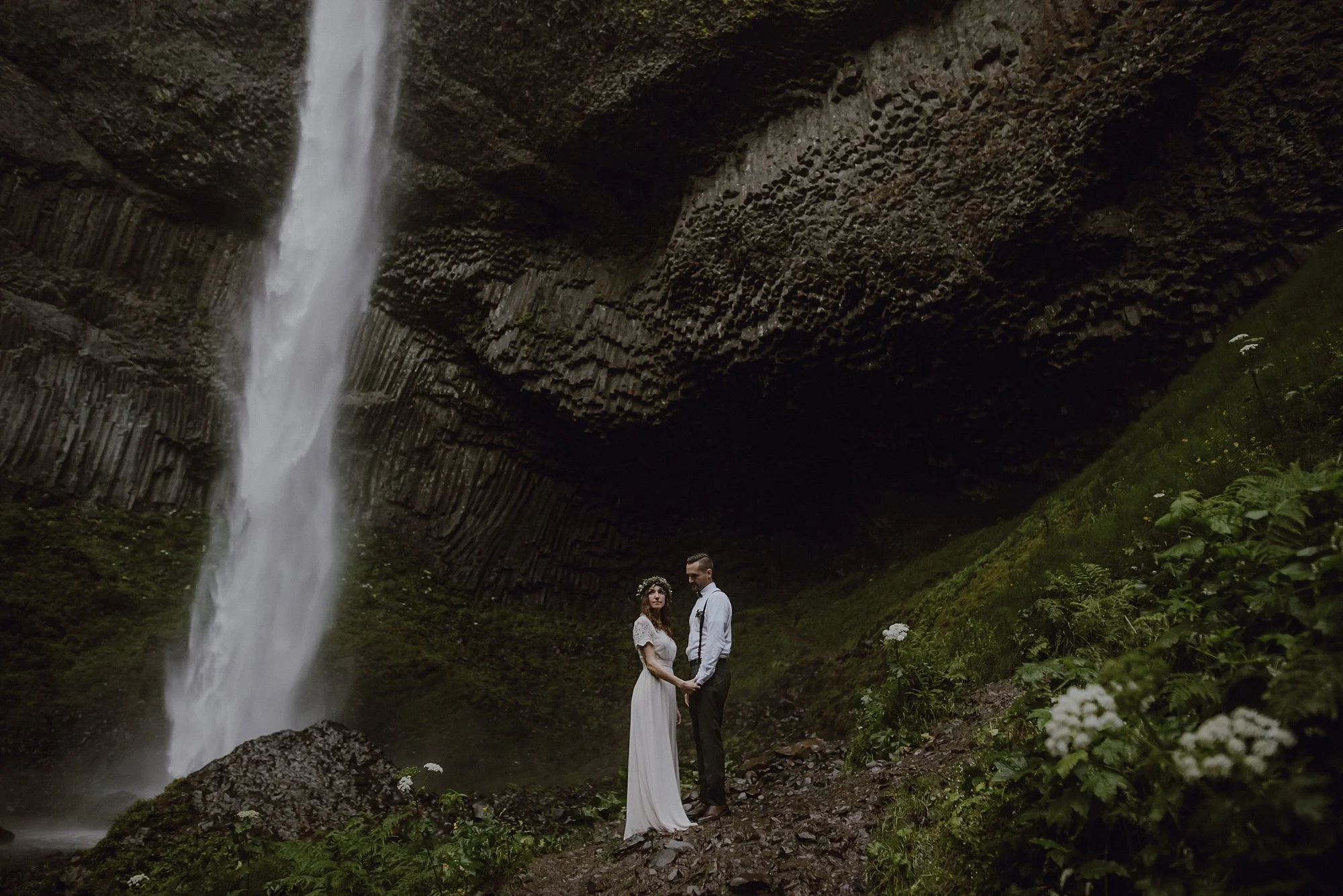 A photo of a bride and groom in front of a waterfall.