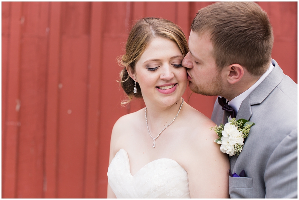 wedding portrait of bride and groom in front of red barn