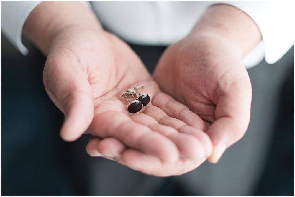 groom holding cuff links on wedding day