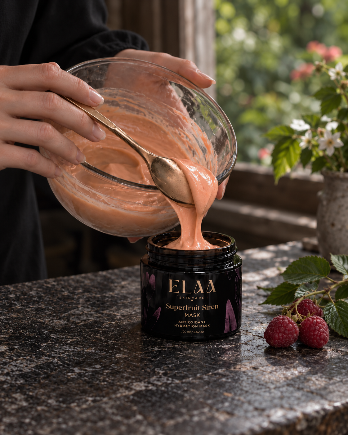 A black tray with skincare products, including ELAA Golden Sunrise Cleanser and Facial Oil, surrounded by flowers, leaves, and crystals, set against a dark background.