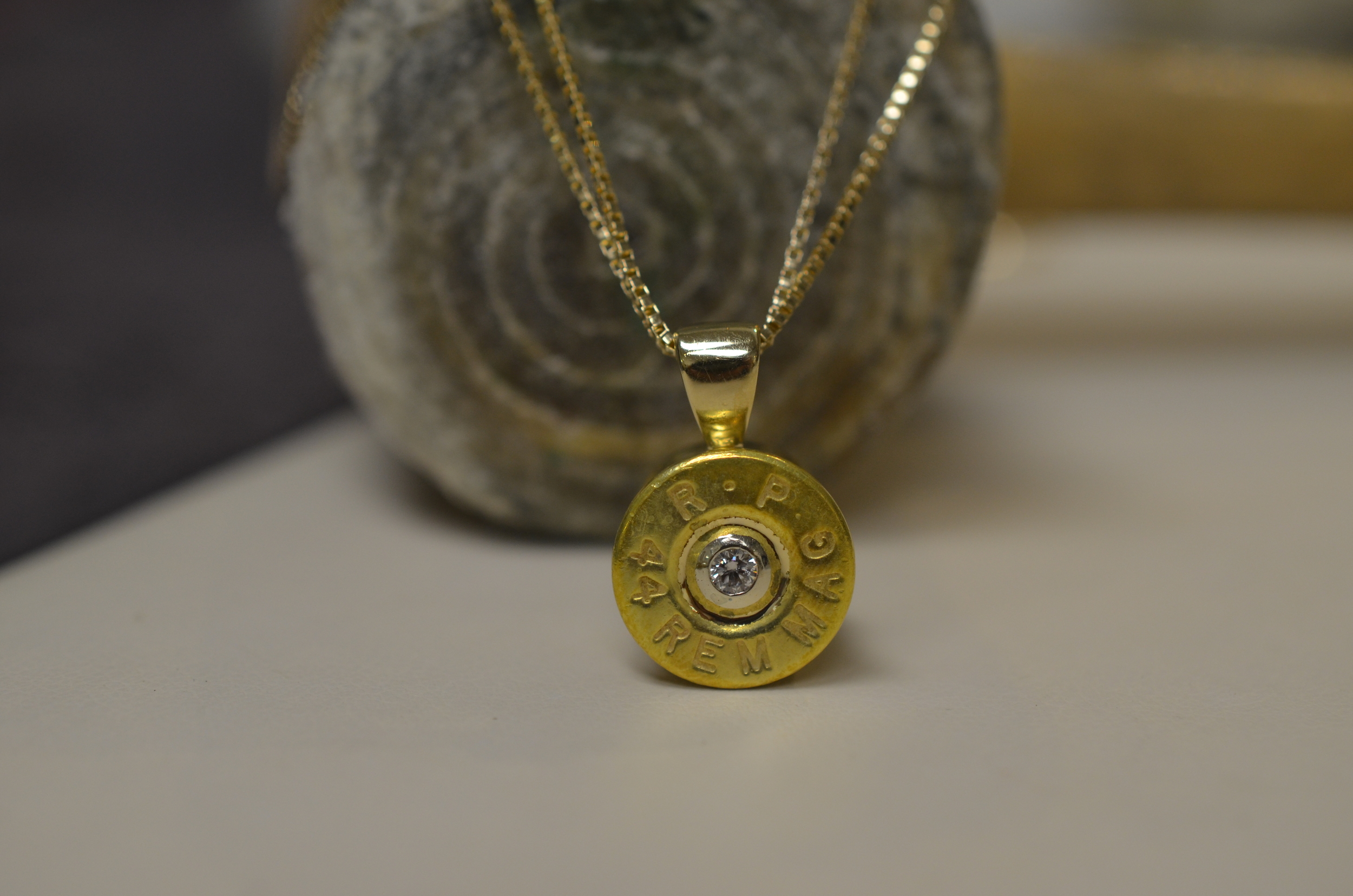 A custom diamond pendant, made from a 44 Magnum bullet casing on top/14K yellow gold back and bail.