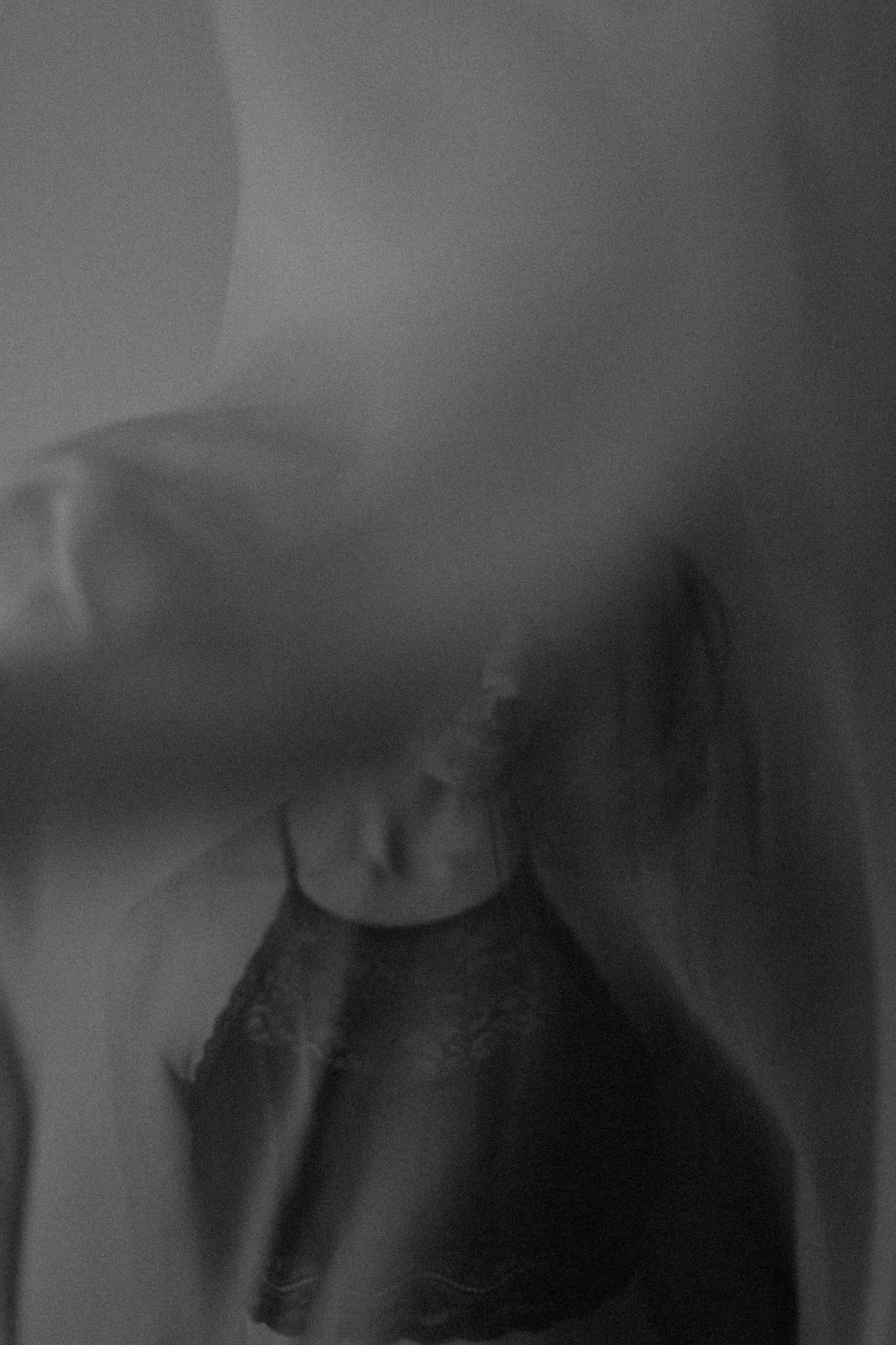 a black-and-white portrait of emma grimsley in a victorian airbnb in dayton, ohio. a piece of fabric is floating through the air in front of her face. there is gentle movement, and emma is clothed in a black lace crop top bralette. photograph by sarah rose walk of sarah rose photography.