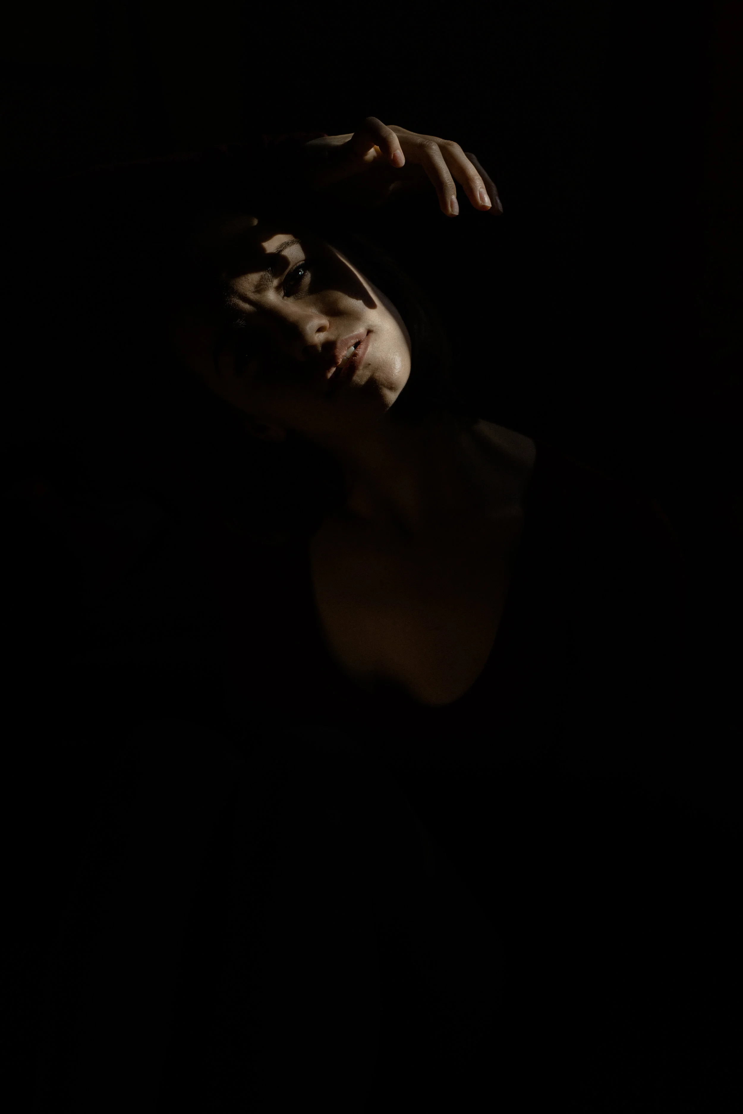 a portrait of emma grimsley in a victorian airbnb in dayton, ohio. photograph by sarah rose walk of sarah rose photography. emma is sitting on the ground, and she is looking to the side, twisting her body. her face and hands are close, as they rest in a sun spot. emma is wearing a long sleeve burgundy red bodysuit.