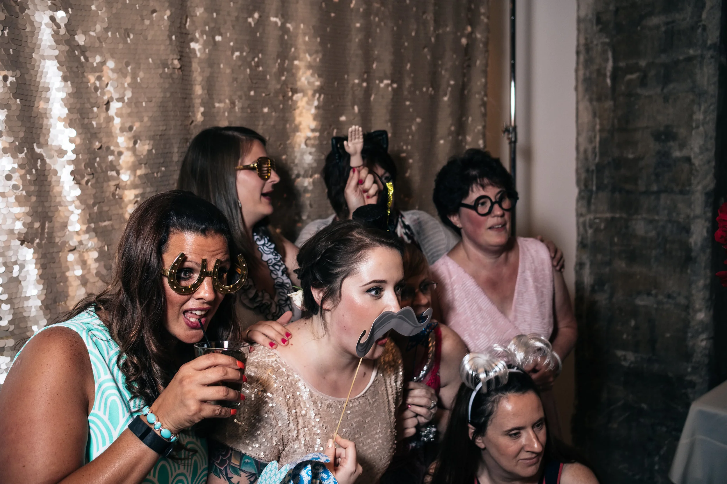Bride gets in the photobooth with friends during her wedding reception in Toledo, Ohio after her destination wedding in Hawaii.