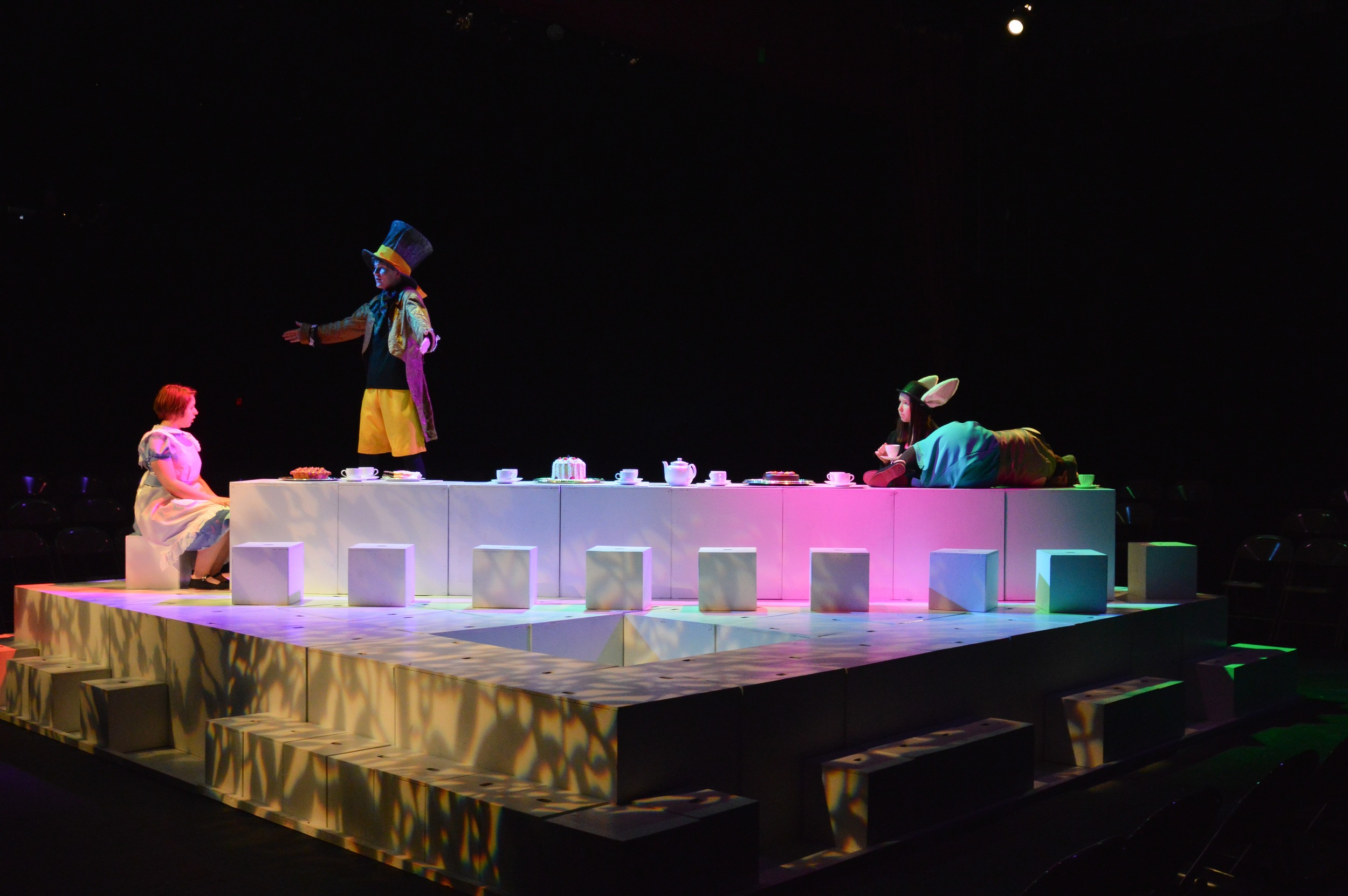OUR SET CONSISTS OF 128 WHITE CUBES WHICH ARE UTILIZED IN VARIOUS WAYS TO DEPICT ALL THE LOCATIONS AND ELEMENTS OF WONDERLAND. CHARLES DODGSON WAS A UNIVERSITY PROFESSOR OF MATHEMATICS WHICH ACCOUNTS FOR THE HUGE ROLE LOGIC AND NUMBER PUZZLES PLAY IN THE BOOK. OUR GEOMETRIC SCENIC DESIGN IS A TRIBUTE NOT ONLY TO THIS MATHEMATICAL ELEMENT BUT ALSO TO THE IMPORTANCE OF IMAGINATION AND INVENTION IN ALL OF ALICE’S ADVENTURES.