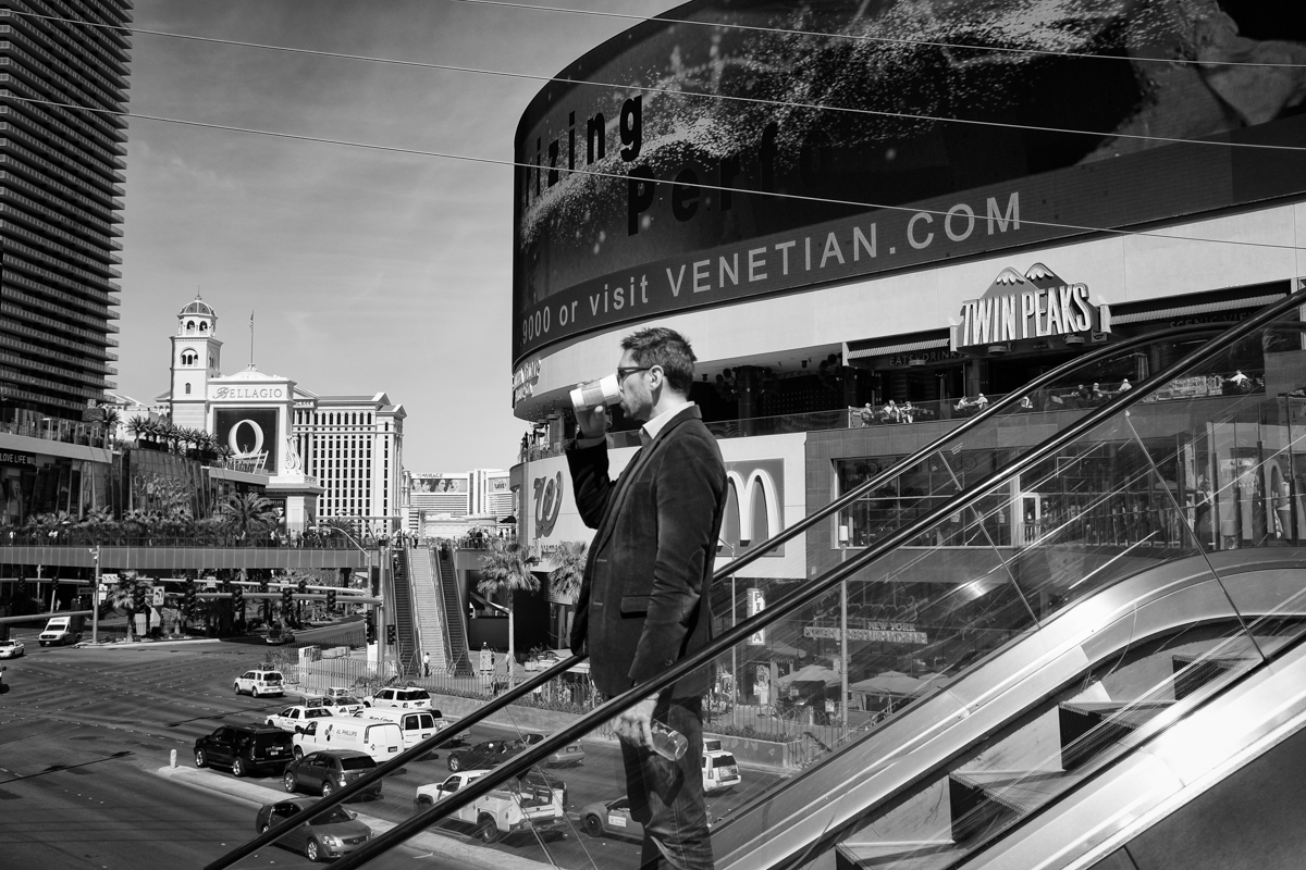 Guy drinking coffee while riding the escalator. 