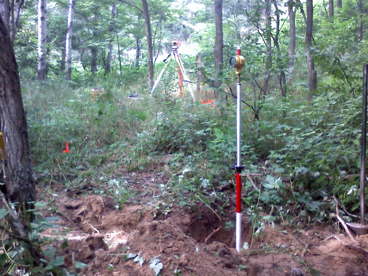 In this picture a tripod is set over a Forest Service Monument, with the prism pole set next to the Fargo Pipe. 