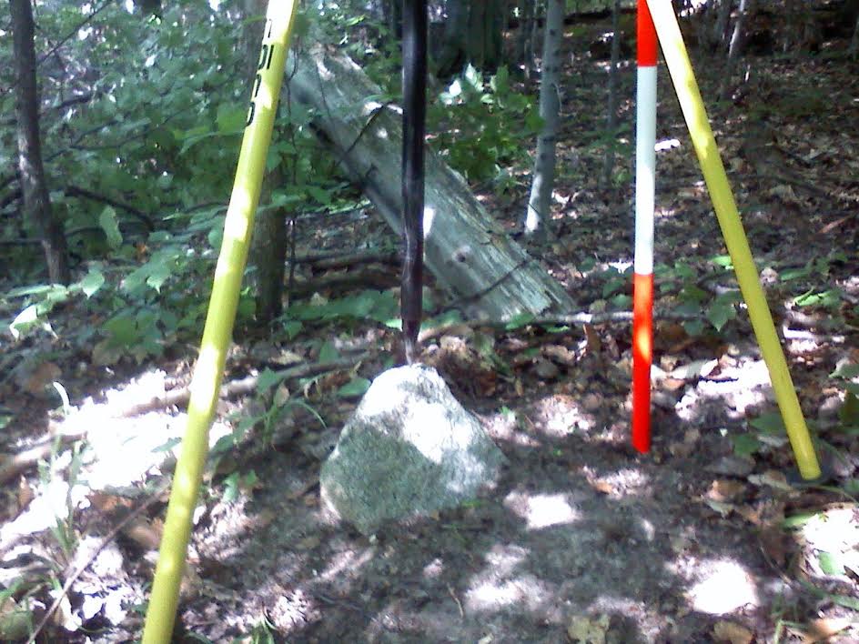 Deputy County Surveyor in Oceana County, S. Edson 1883 Set 'A light-colored stone 22 in. length and 8 by 10. placed small point (up)'. South Center 1/16th Corner, Section 35, Claybanks Township. A rotted off fence post seen in back (orange and white range pole stuck in the decayed base) with old wire fence intersection running E+W+N. Found in July 2014
