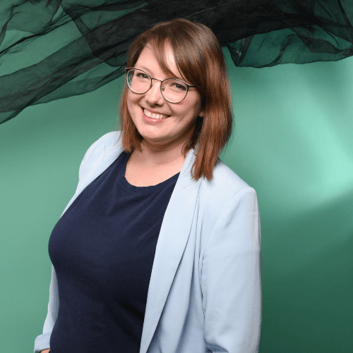 Ines schaut in die Kamera und lächelt fröhlich.