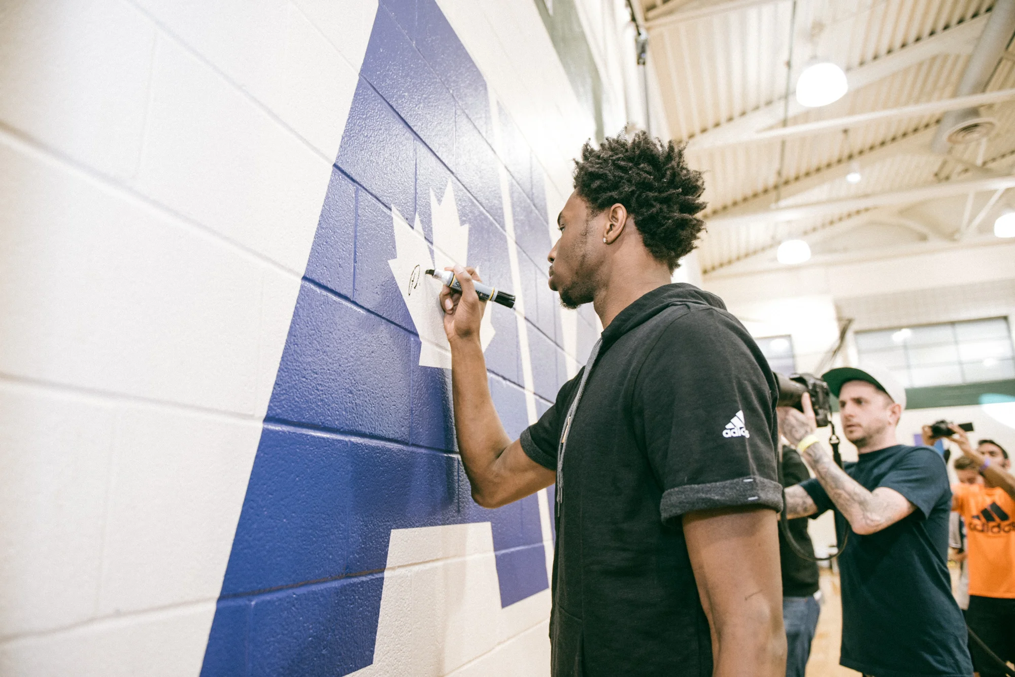 Andrew Wiggins signs his newly unveiled logo at the Dufferin Clark Community Centre gym