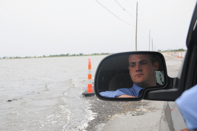Photo by Rainforest Action Network / Creative Commons. Chris Chaisson of the United Houma Nation eyes the waves as water covers half the road to Isle de Jean Charles in the Louisiana bayou.
