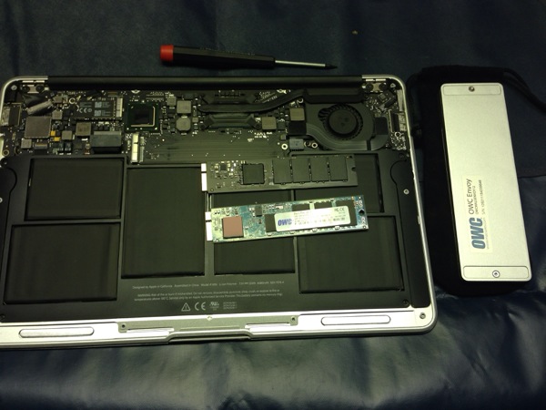 MacBook Air with the base removed. The original 120GB Toshiba SSD is remove and below it you can see the OWC 240GB SSD ready for fitting. You can see the OWC Envoy enclosure to the right.