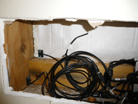 A sensor configuration installed within a wall cavity. Moisture sensors have been installed at the base of the stud as well as the back of the cladding, with a temperature sensor taped to the building paper.