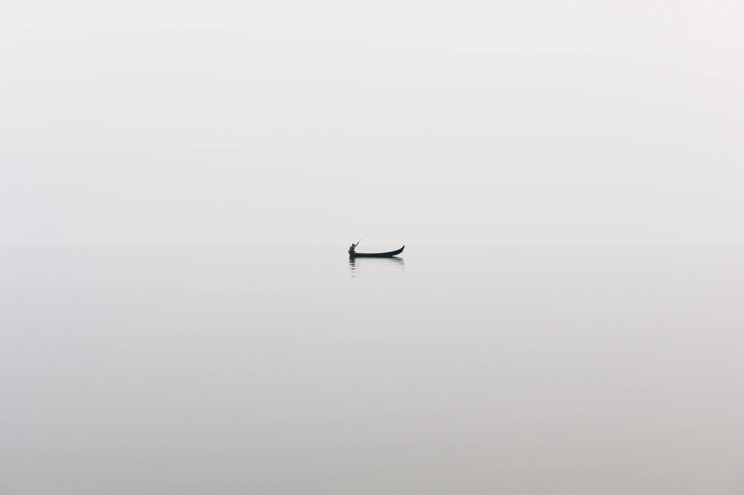Burma A fishing boat on a perfectly calm Indawgyi lake in northern Burma on a misty afternoon.
