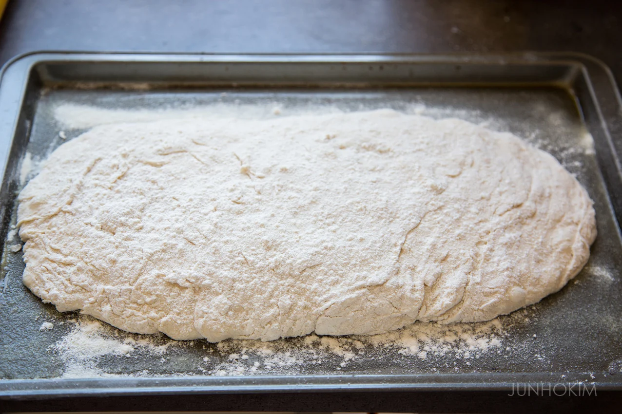 Place the dough on the pan and add flours on the top of the dough