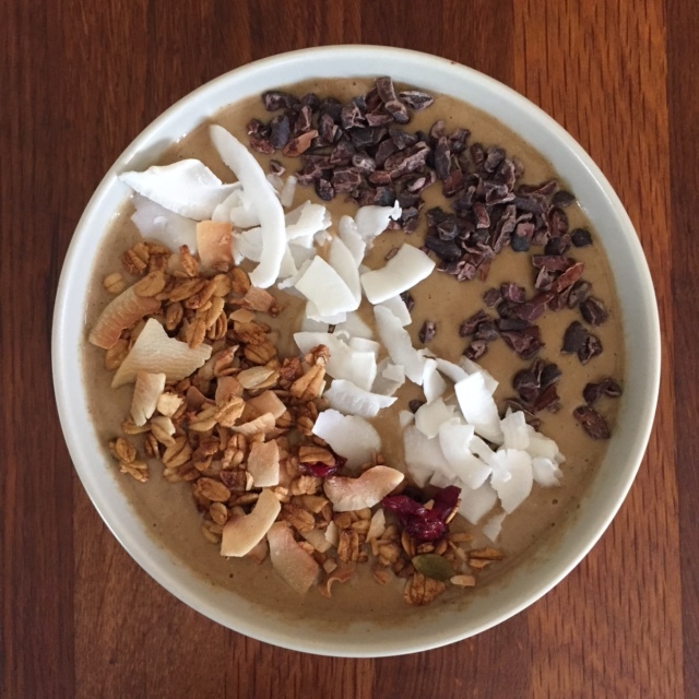Chocolate smoothie bowl with raw cacao nibs, coconut flakes, and gluten-free coconut granola 