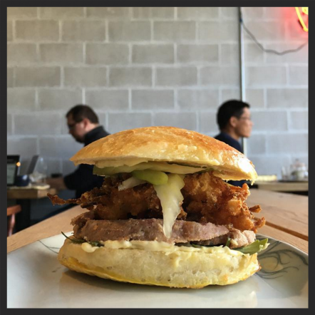 Porkhead terrine, jalepeño-pickled celery, fried onions and shrimp mayo on a sweet roll at Loyal Nine | Instagram @loyalninecafe