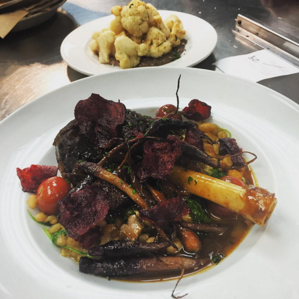 Braised lamb shank with navy beans, bacon, cherry tomatoes & arugula, finished with beet chips | Instagram @angeline_nola