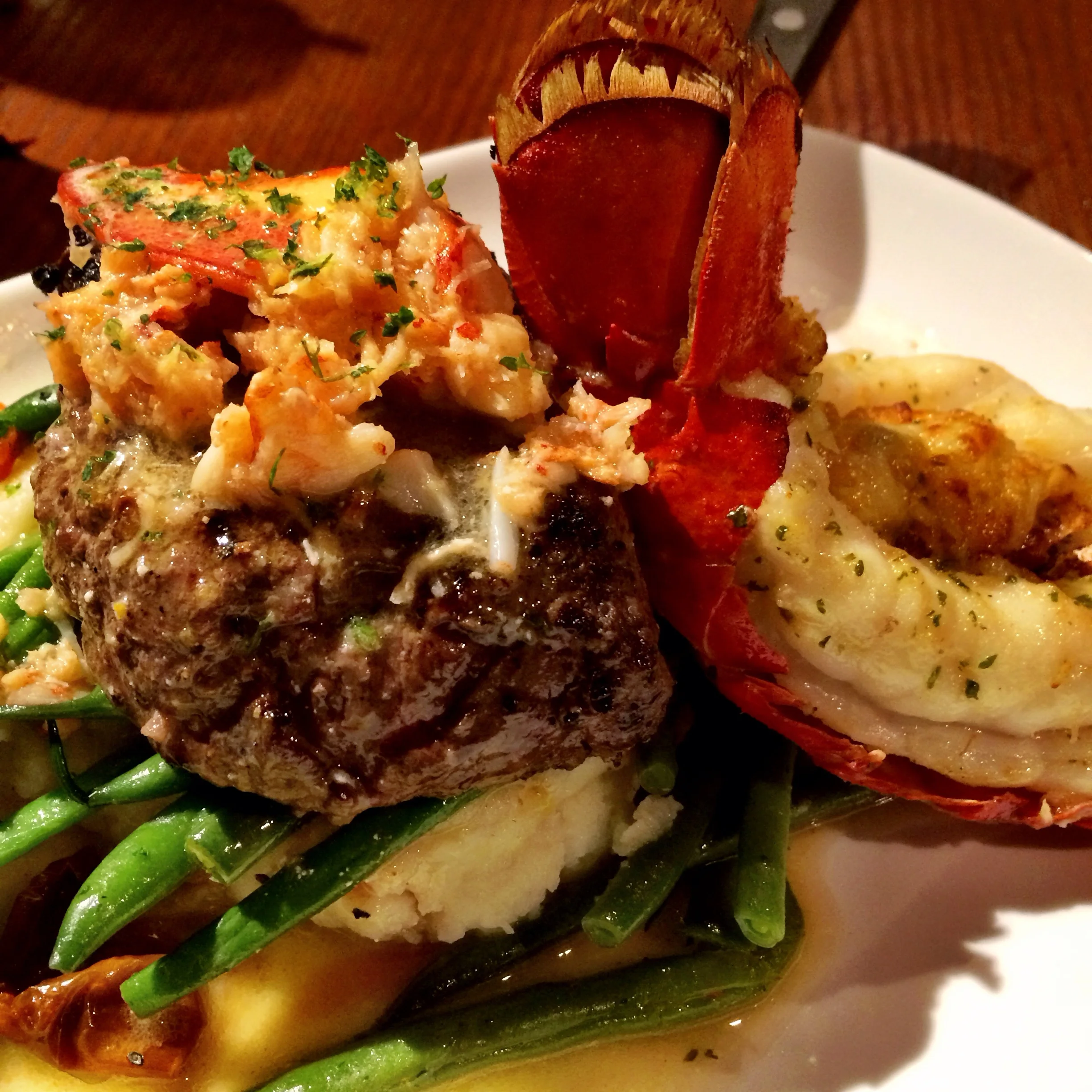 Ultimate Surf and Turf. A Maine lobster tail baked with crab-and-seafood stuffing paired with a peppercorn-seasoned grilled sirloin topped with Maine lobster meat in a citrus-hollandaise sauce. Served over mashed potatoes, roasted tomatoes and green beans 