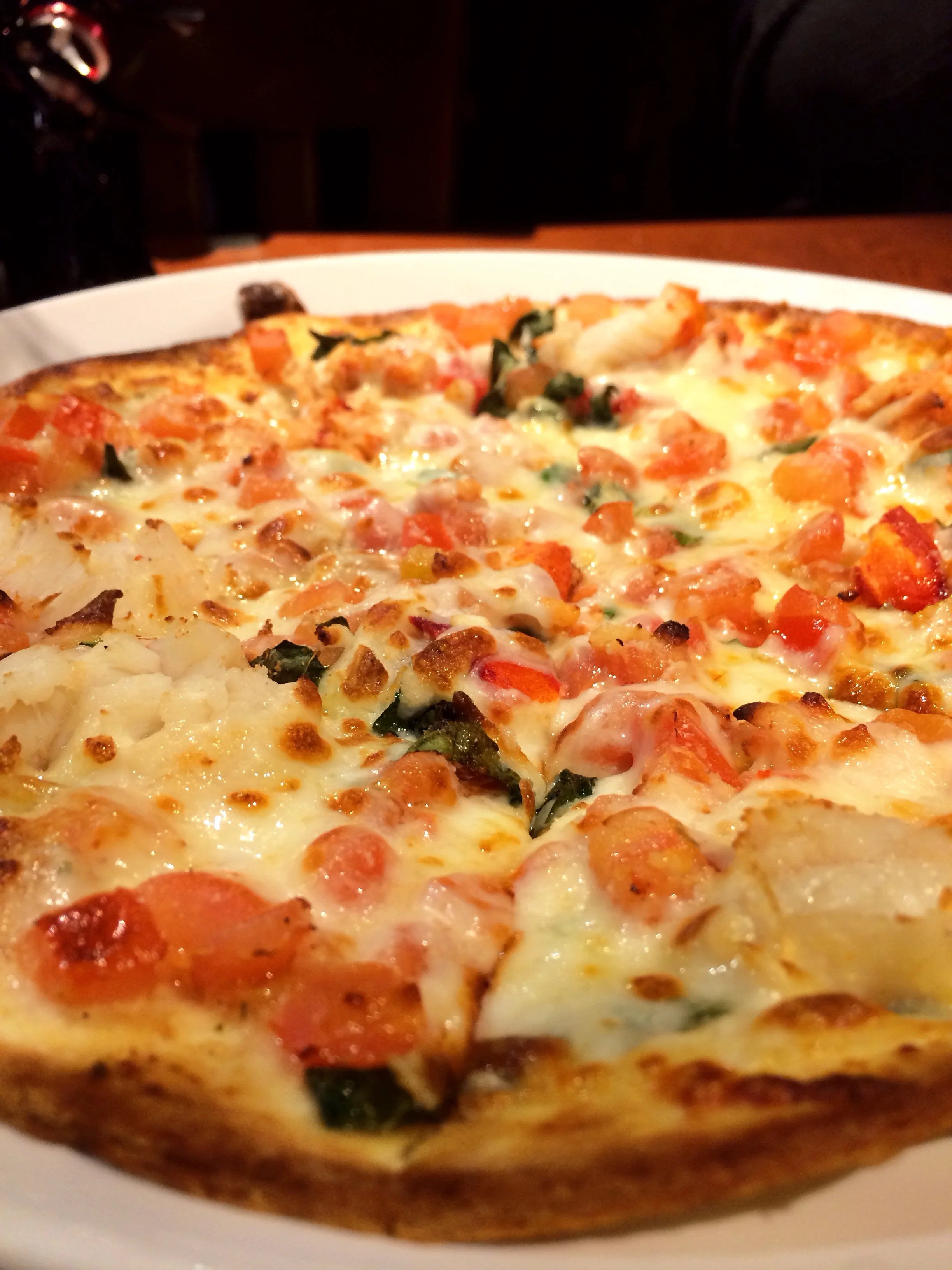 Lobster Pizza. A crisp thin-crust pizza topped with langostino lobster meat, melted mozzarella cheese, fresh tomatoes and sweet basil