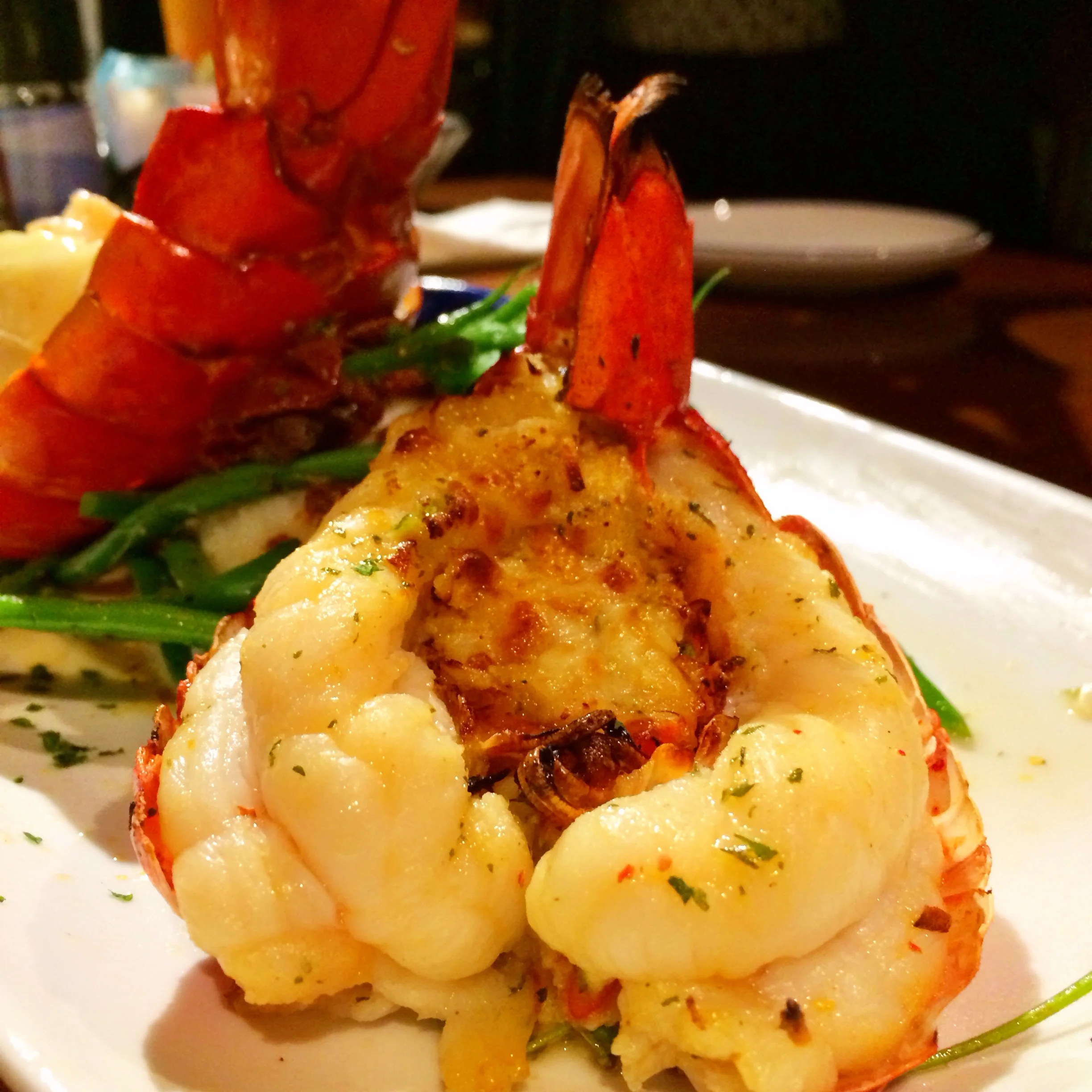Dueling Lobster Tails. A roasted Maine lobster tail topped with tender shrimp in a creamy garlic sauce paired with a golden-baked Maine lobster tail with crab-and-seafood stuffing. Served over mashed potatoes, roasted tomatoes and green beans