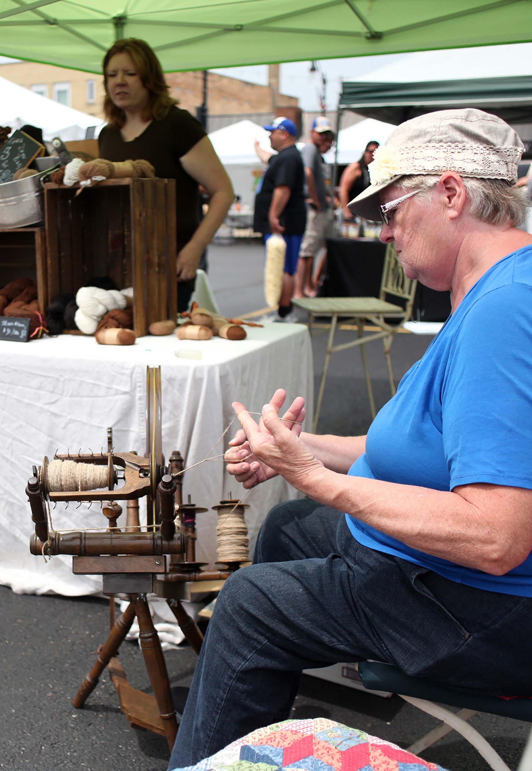  Leslie McHugh, left, runs their farm booth Saturday during the Kankakee Farmers Market in downtown Kankakee while Rosie McHugh spins yarn from their families alpaca herd. The farm was established in 2007 in rural Martinton, and is home to an alpaca 