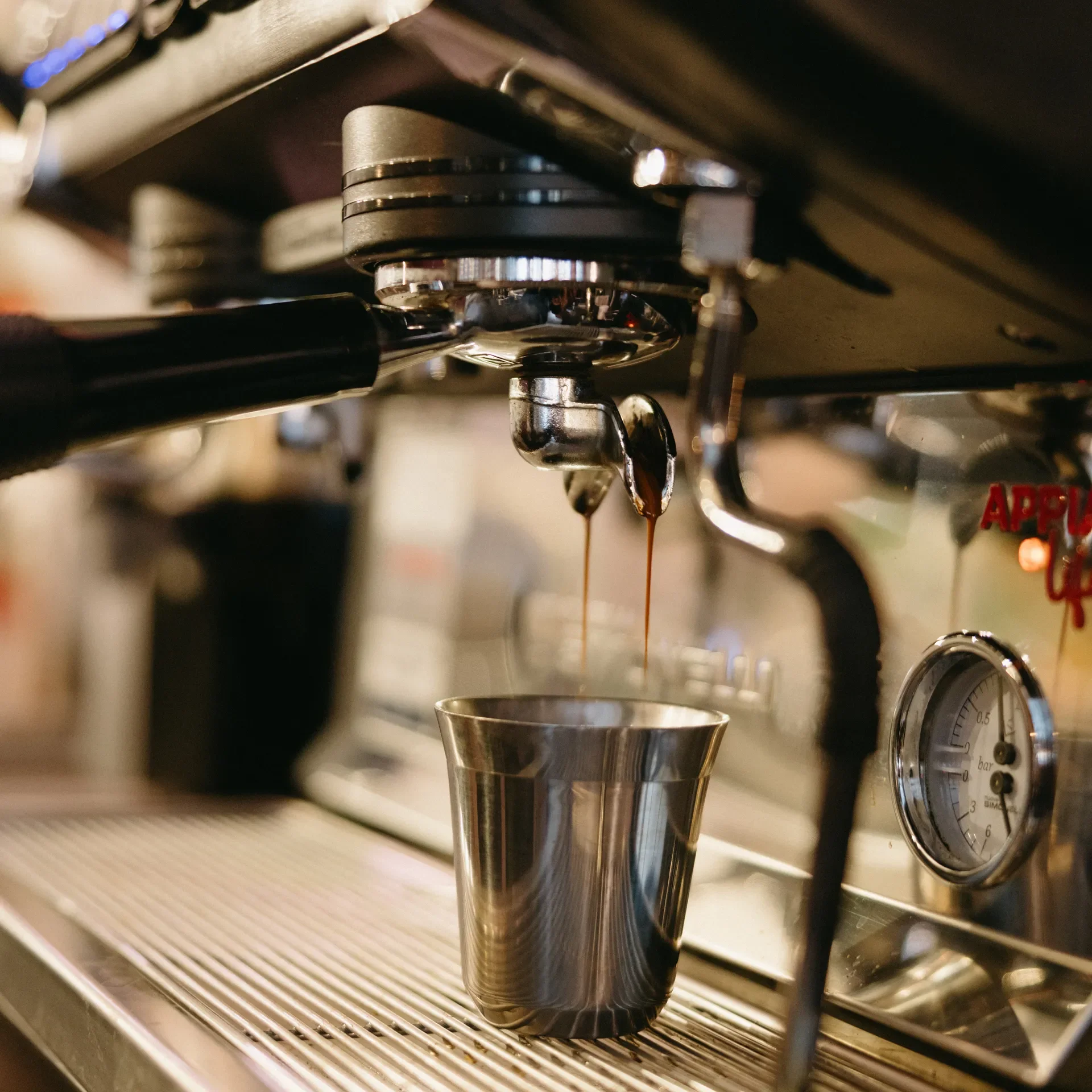 Fresh espresso pours from a commercial portafilter into a stainless steel cup, capturing the rich crema and precision of Raleigh Raw’s craft coffee. A close-up look at the artistry behind our bold, freshly pulled espresso shots.