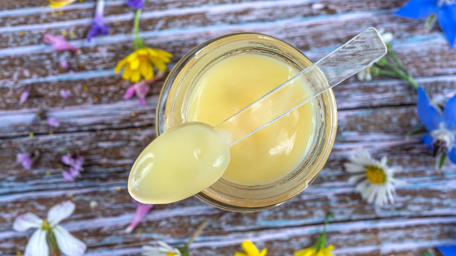 Jar of creamy royal jelly with wildflowers