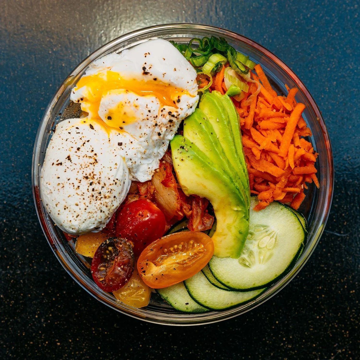 Bowl with poached eggs, avocado, veggies, and kimchi