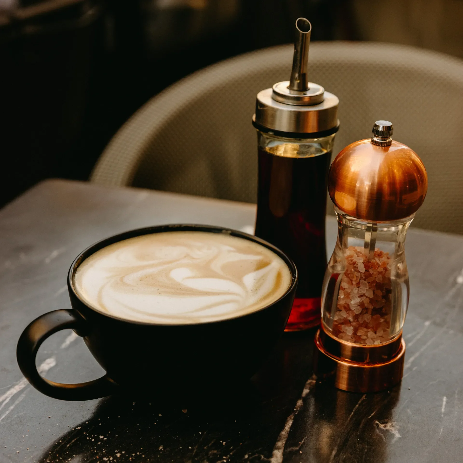 A handcrafted latte with delicate art served in a black mug alongside Himalayan salt and house-made syrup at Raleigh Raw. A cozy, artisanal café moment highlighting intentional ingredients and warm, earthy coffeehouse vibes.
