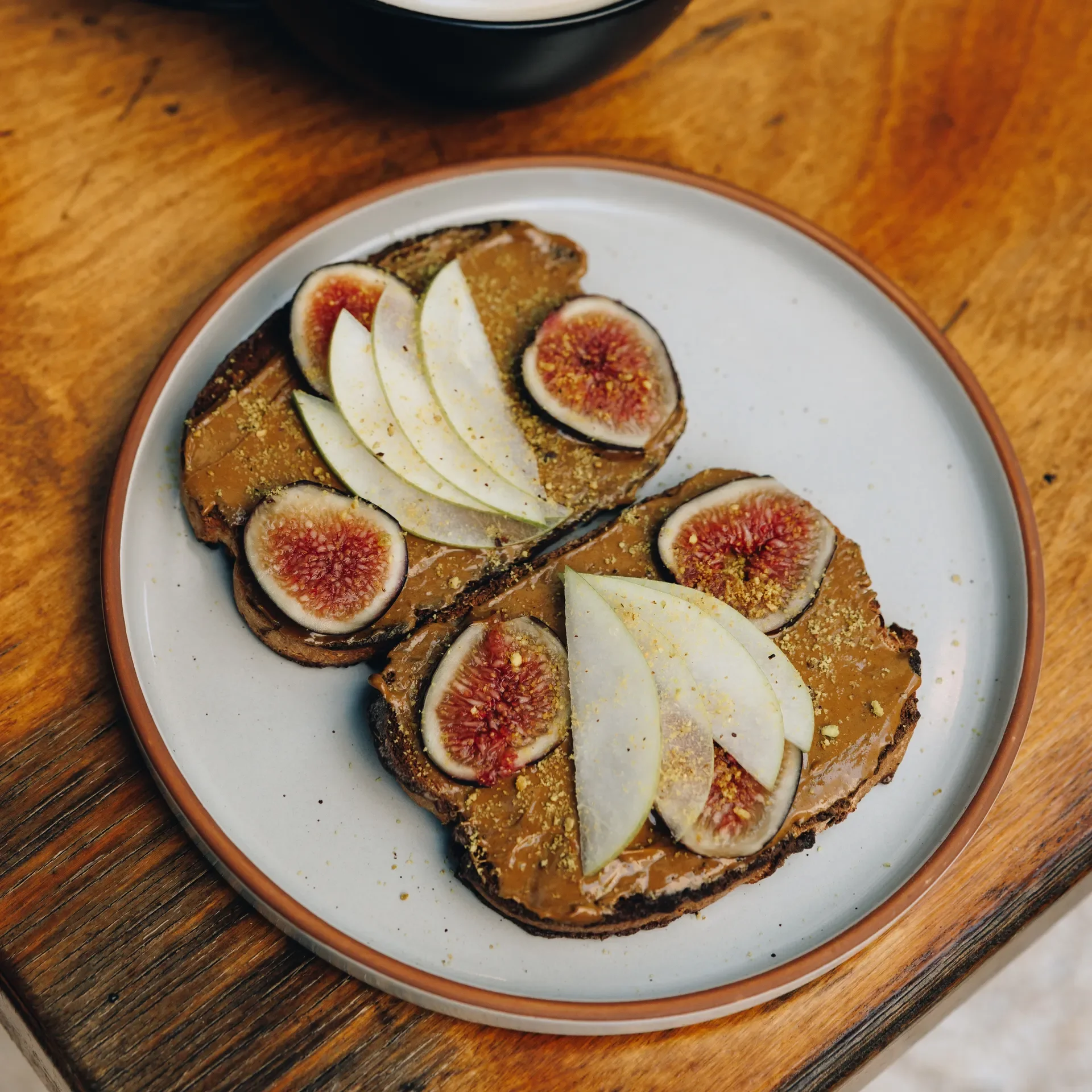 Fresh fig and pear slices layered over creamy pistachio butter on hearty toast. A clean, gluten-free, soy-free, refined-sugar-free Raleigh Raw breakfast made with simple, nourishing ingredients for natural energy and everyday wellness