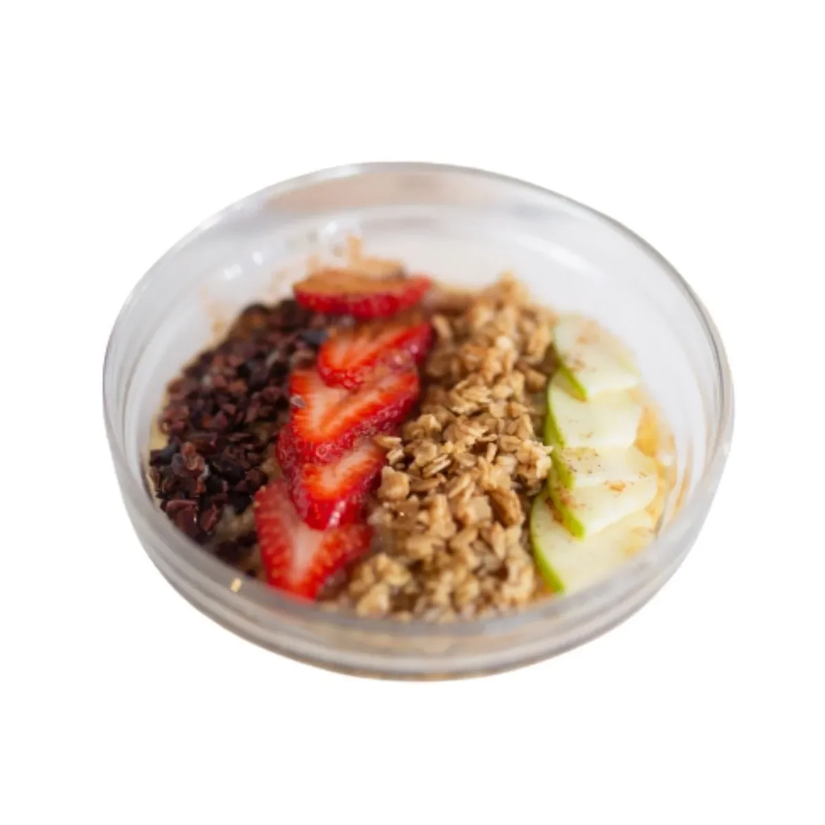 A clear glass bowl filled with oatmeal and topped with rows of sliced strawberries, granola, cacao nibs, and thinly sliced apples, shot on a white background with bright, clean lighting.
