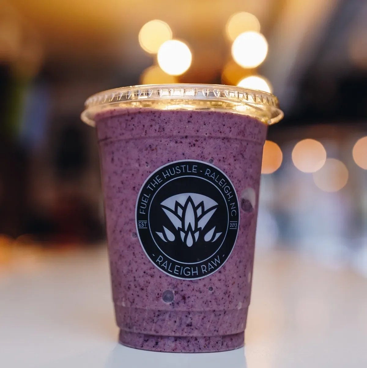 The Blueberry Bee Pollen Smoothie at Raleigh Raw blends almond milk, blueberries, bee pollen, banana, maca, and raw honey for a creamy antioxidant-rich boost. Finished with a bee pollen garnish for natural sweetness and superfood energy.