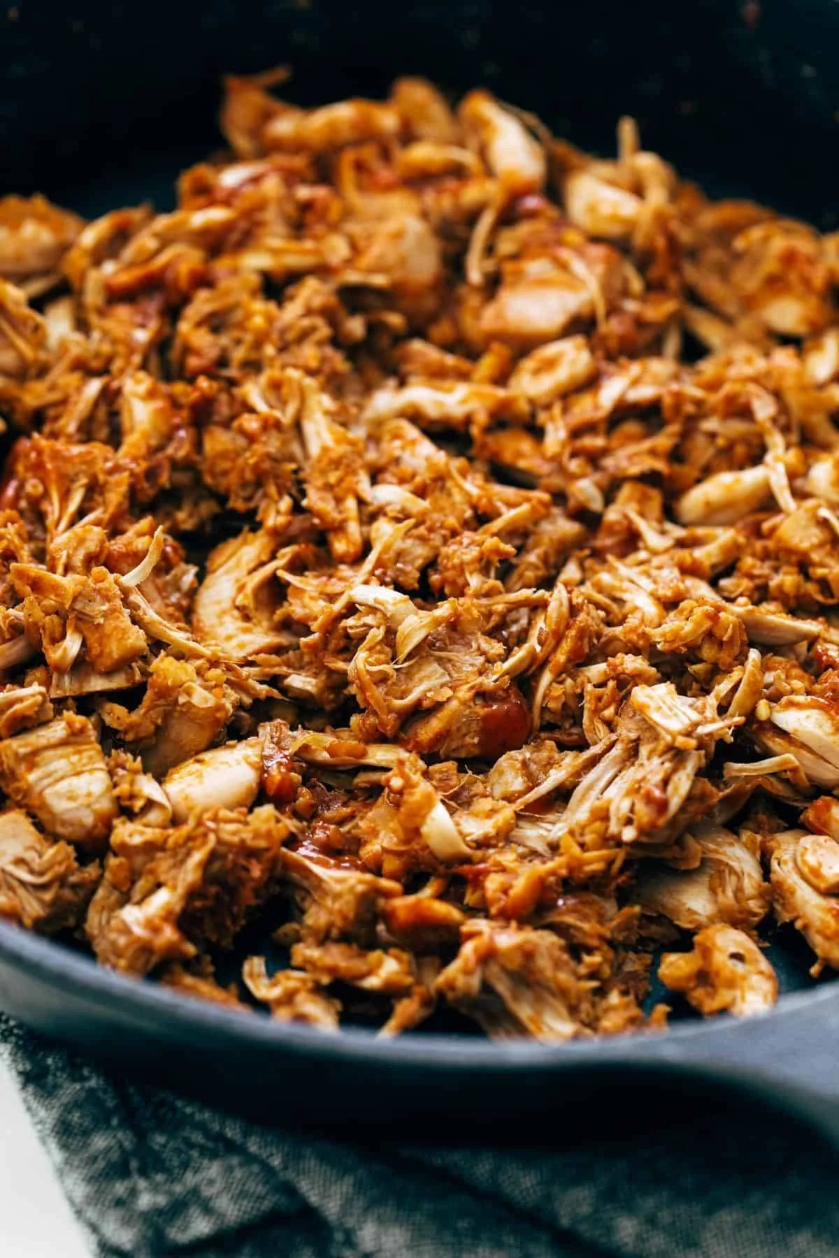 Close-up of shredded BBQ jackfruit cooking in a skillet, coated in a rich, smoky sauce.