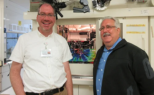 Researchers Drs. Tim Henrich and Henry VanBrocklin pose at the amfAR Institute for HIV Cure Research at the University of California, San Francisco, in a facility that "tags" proteins for later imaging and study.