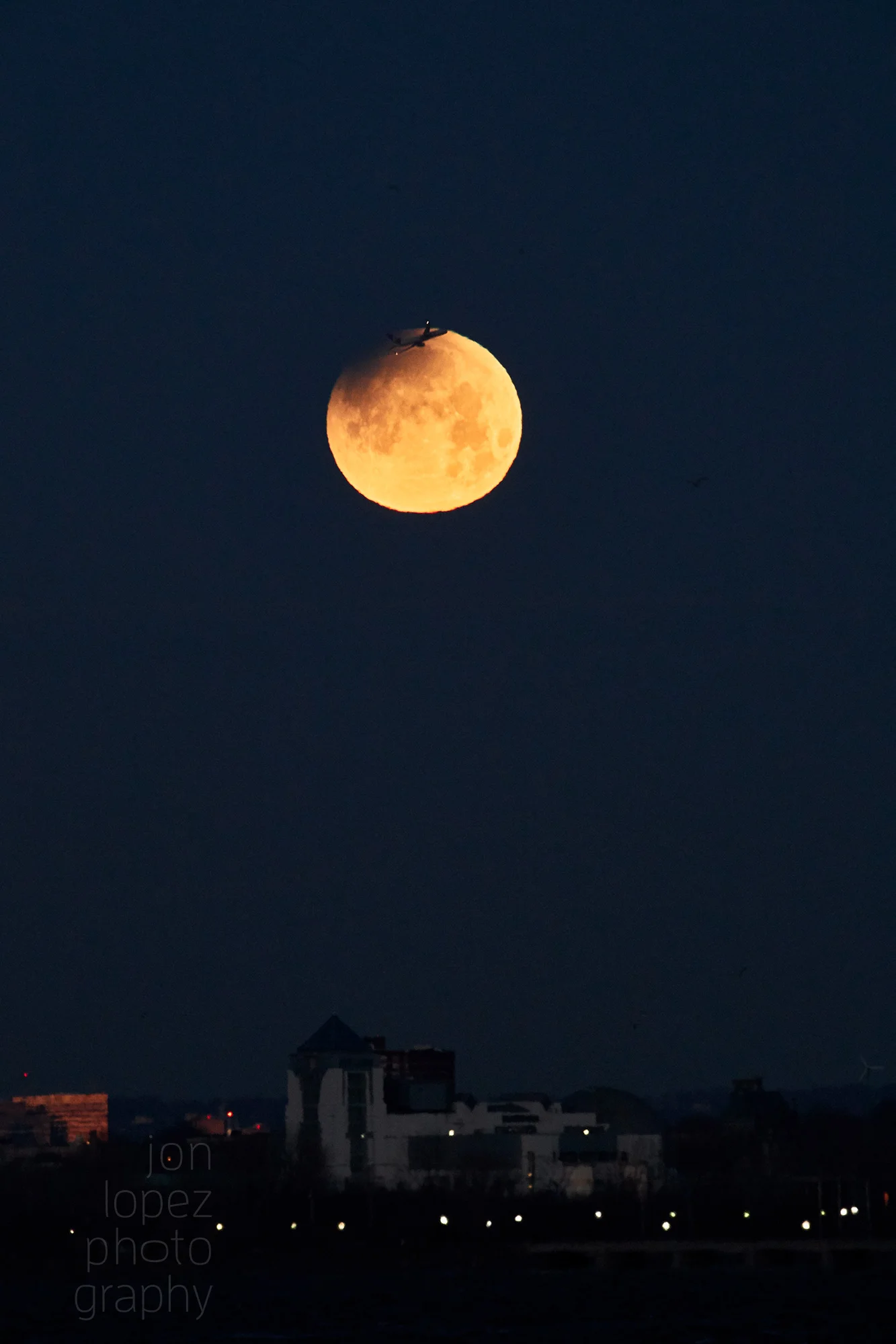 This photograph was taken on my digital camera using a telephoto lens which allowed me to compress the background and draw even closer to the setting super blue blood moon. The airplane flying through was a gift of serendipity and being in position. Photo credit: Jonathan Lopez