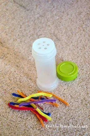 Image Description: An empty spice jar sits on the floor next to some small pipe cleaners.