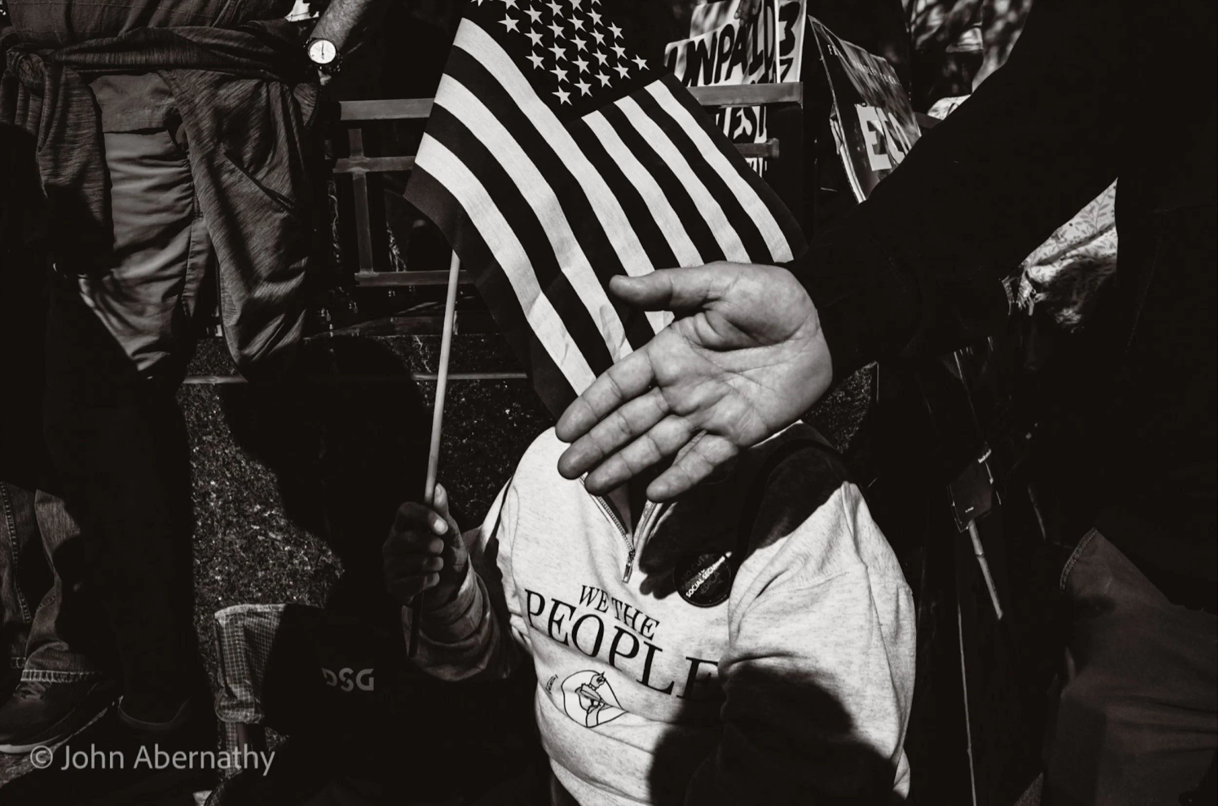 This is at the No Kings protest in Minneapolis. The mouth behind the hand is telling me I need to ask before I take a photo. There’s 100,000 people in the street packed shoulder to shoulder. There’s probably over 99,000 cell phones. And p