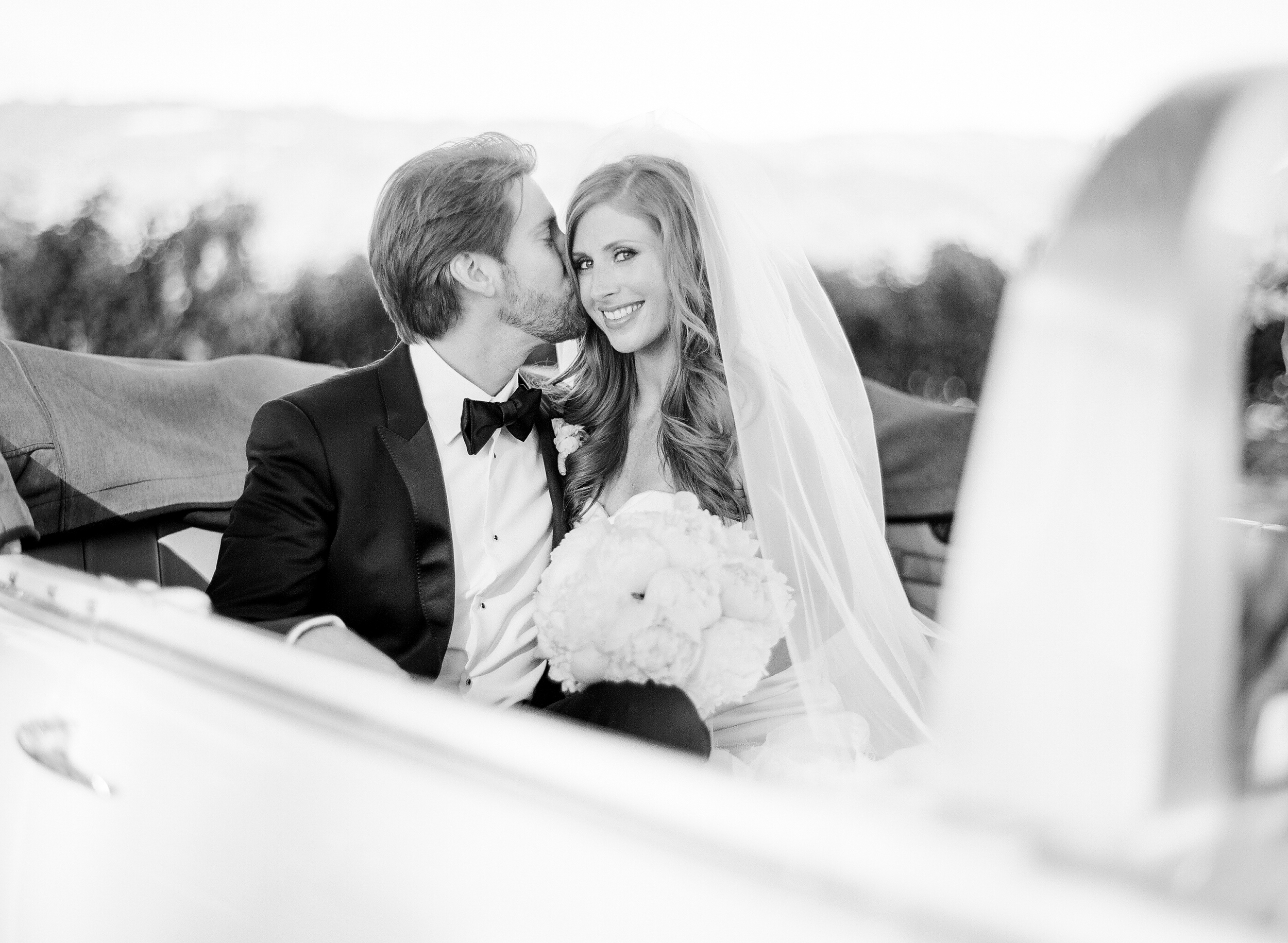 Michael kisses his bride in the backseat of a convertible vintage car during a just-married couple shoot with Sylvie Gil