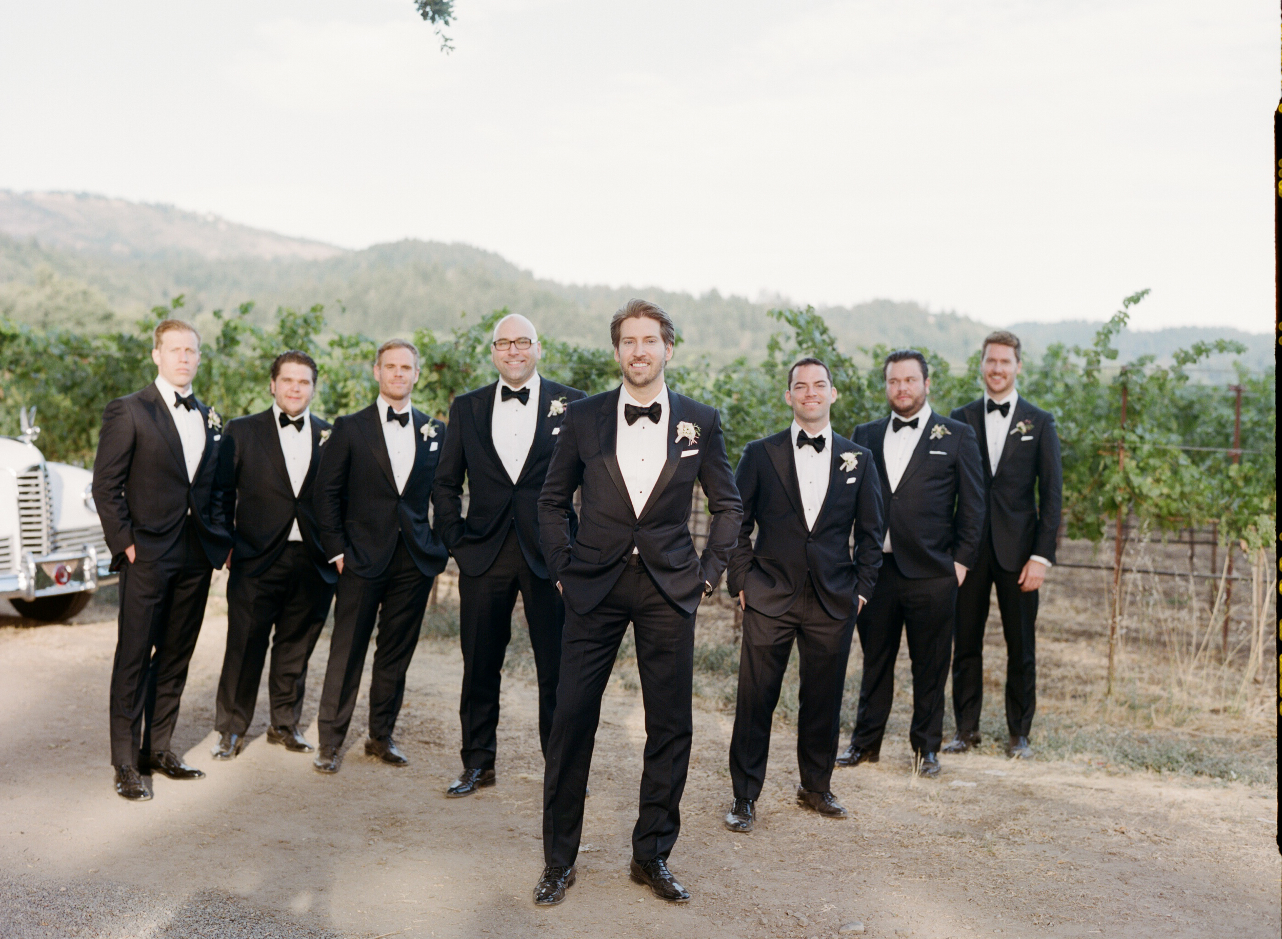Michael poses with his groomsmen, all handsome in black tuxedos; photo by Sylvie Gil