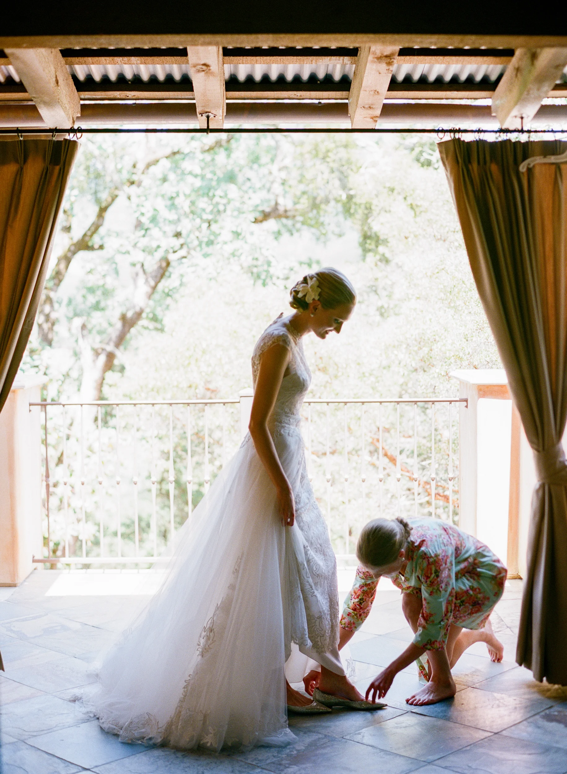 Bride steps into wedding shoes with bridesmaid; Sylvie Gil Photography