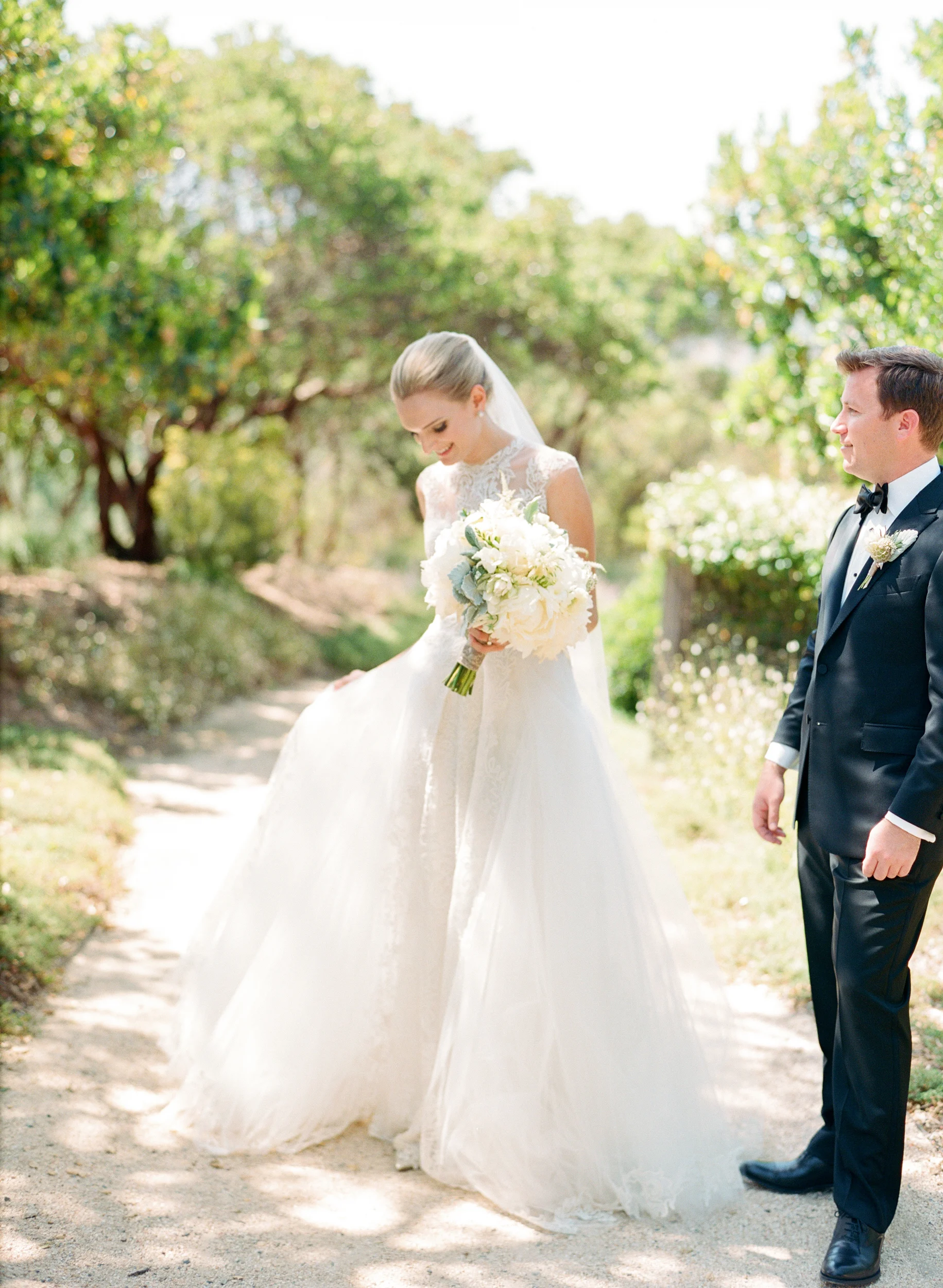 Bride stands with groom,&nbsp;admires her Monique Lhuillier gown; Sylvie Gil Photography