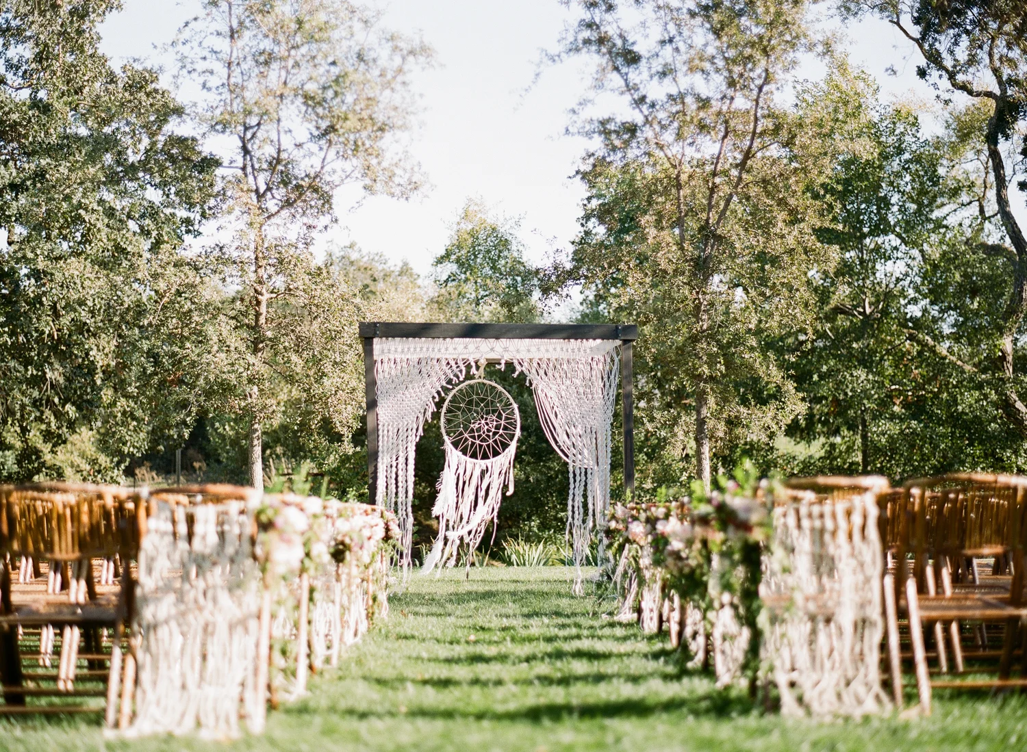 A giant dreamcatcher and macrame hanging decorates the ceremony space at a Napa Valley ranch; Sylvie Gil Photography