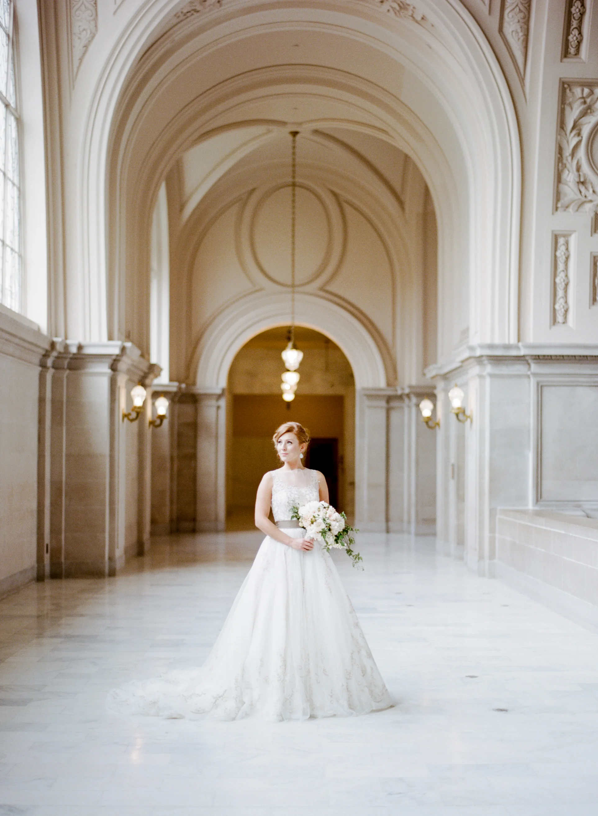 A bride stands in the mezzanine of San Francisco City Hall; Sylvie Gil Photography