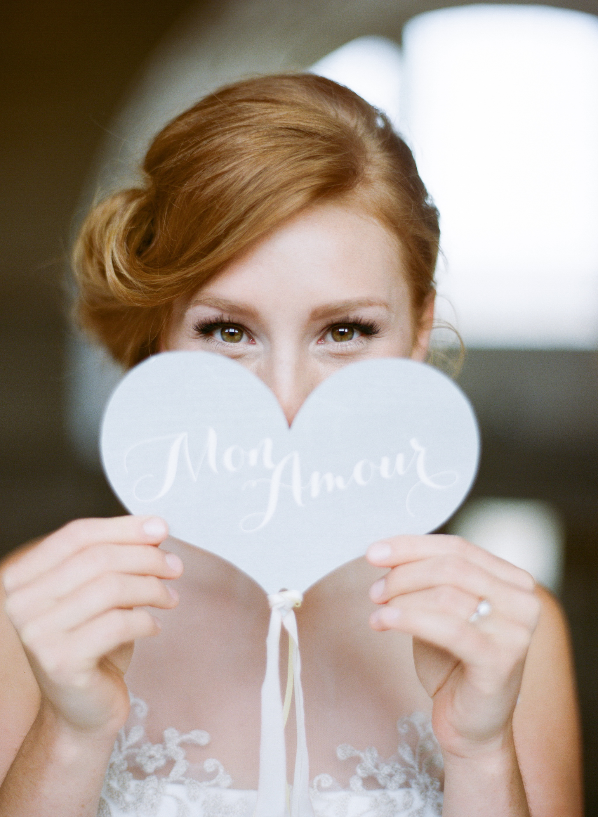 A redhead bride holds up a sign that says "Mon amour"; Sylvie Gil Photography