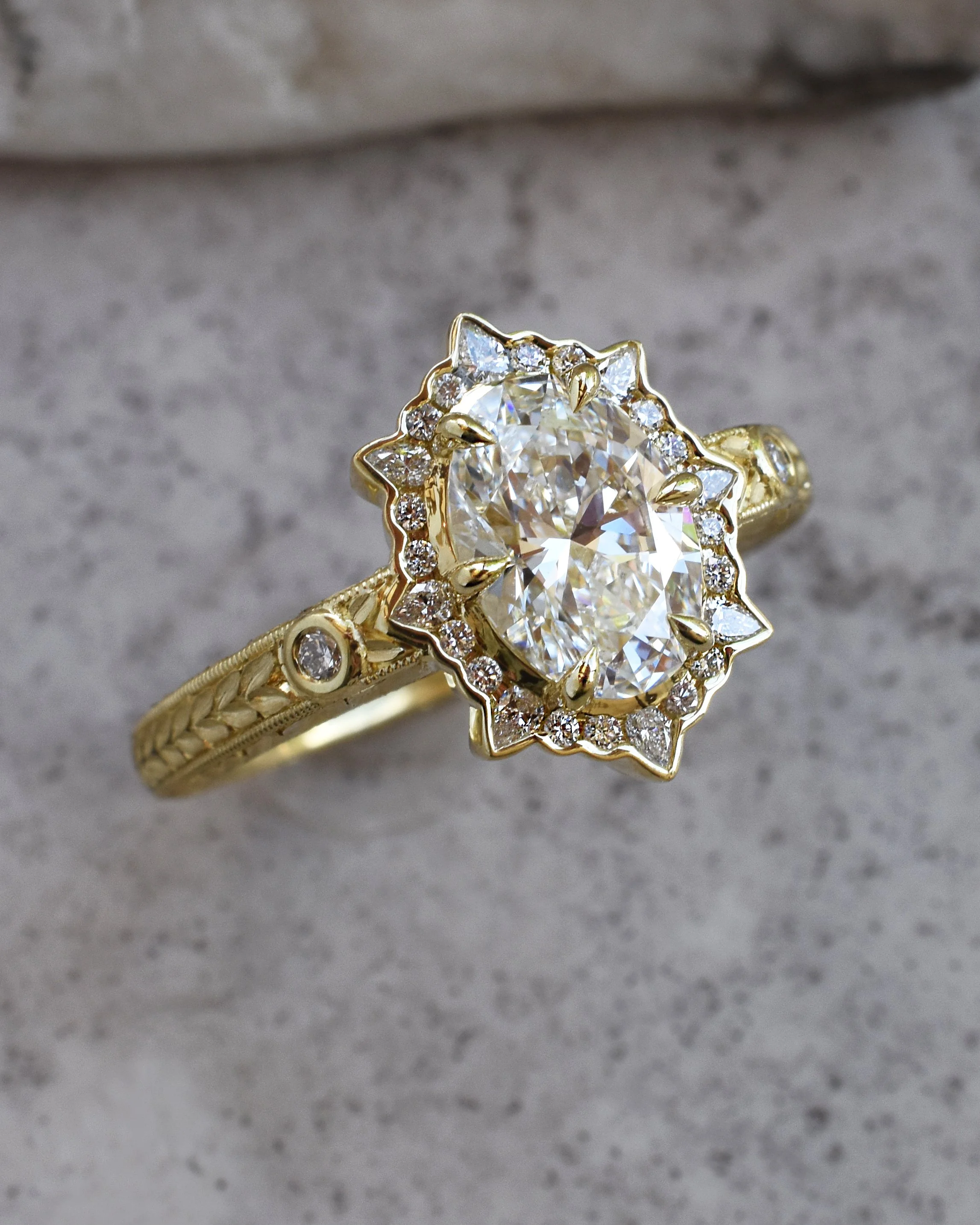 Gold ring with a large central oval lab grown diamond, surrounded by smaller diamonds in a floral pattern.